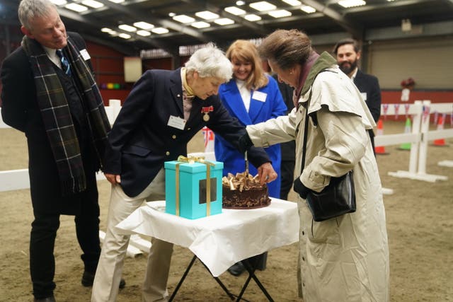 Martin Clunes, left, and Sister Mary Joy Langdon, second left, look on as the Princess Royal cuts a cake during her visit 