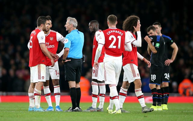 Arsenal players speak to referee Martin Atkinson, who reversed his decision to award them a third goal after consultation with the VAR