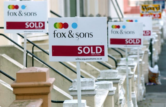 A number of sold signs on steps outside properties