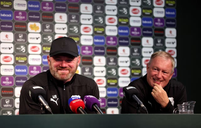 Wayne Rooney, sat in front of microphones, laughs during a press conference