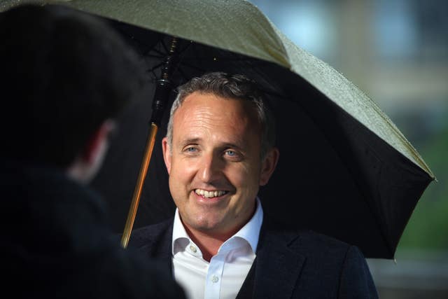 Alex Cole-Hamilton smiling while standing under an umbrella