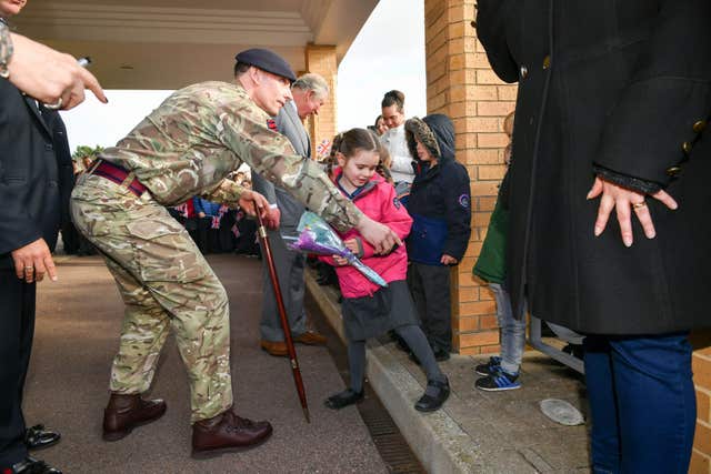 A soldier comes from the crowd and helps Bella Armstrong (Ben Birchall/PA)