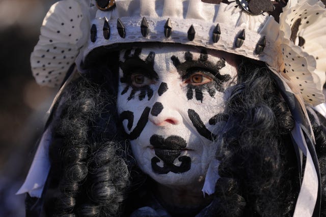 Woman dons striking black and white face paint as a Pig Dyke Molly dance