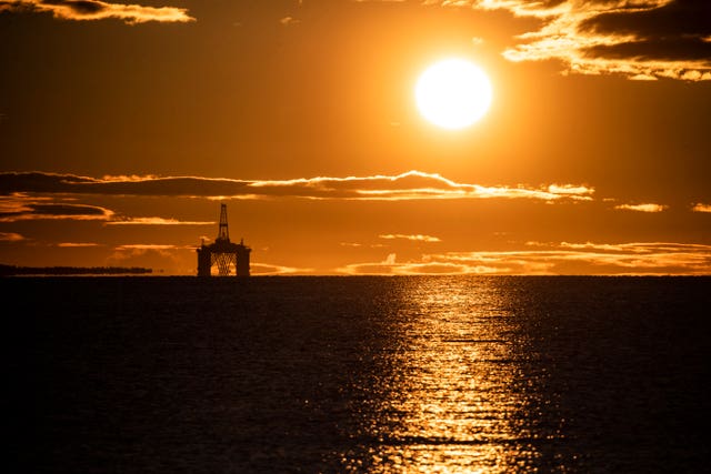 Sun rises behind a redundant oil platform 