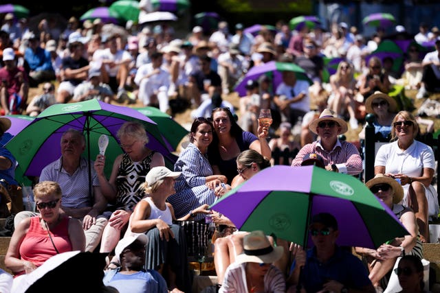 Spectators on the hill shelter from the sun on day 12 of Wimbledon in south-west London 