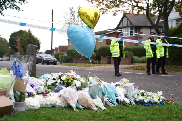 Flower and balloons near a police cordon staffed by officers