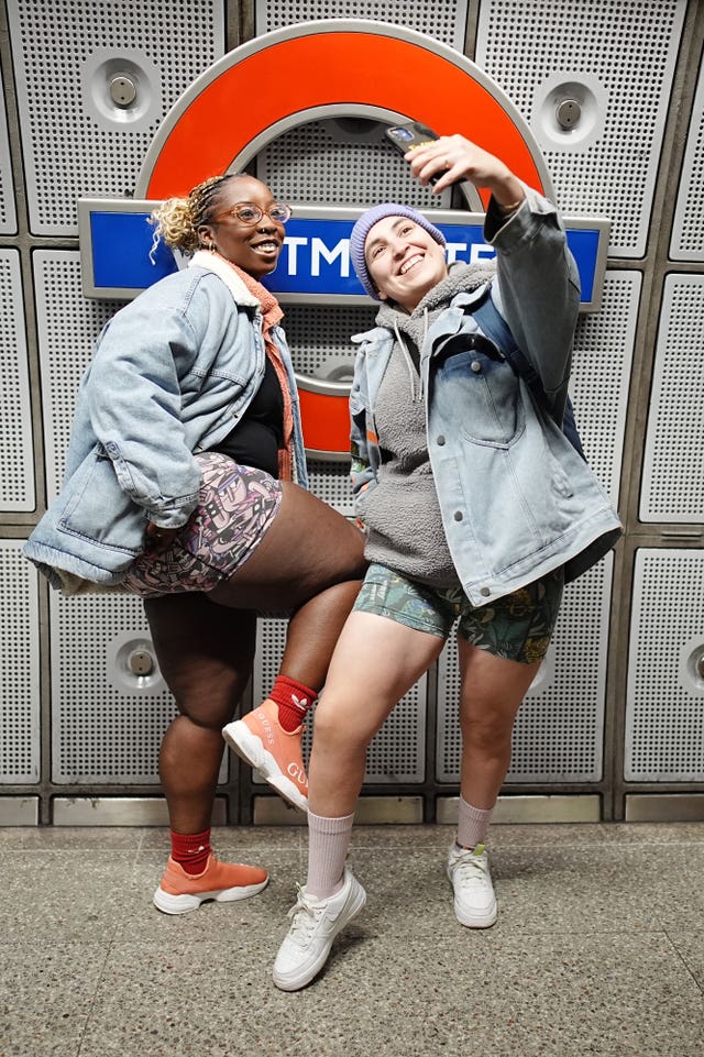 Two women take a selfie on a Tube platform while dressed in a colourful boxers for the annual No Trouser Tube Ride in London 