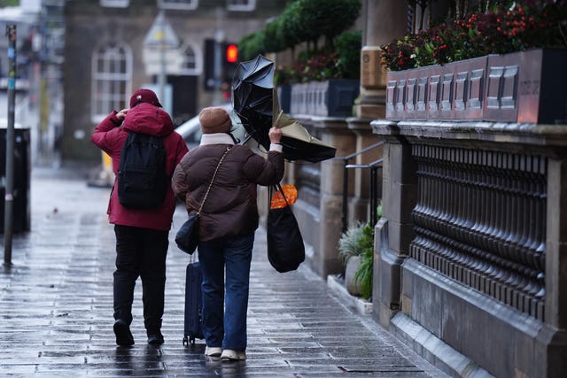 A couple hold an umbrella that has blown inside out