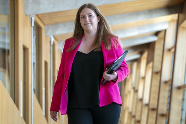 Gillian Mackay in pink jacket, walking through Parliament