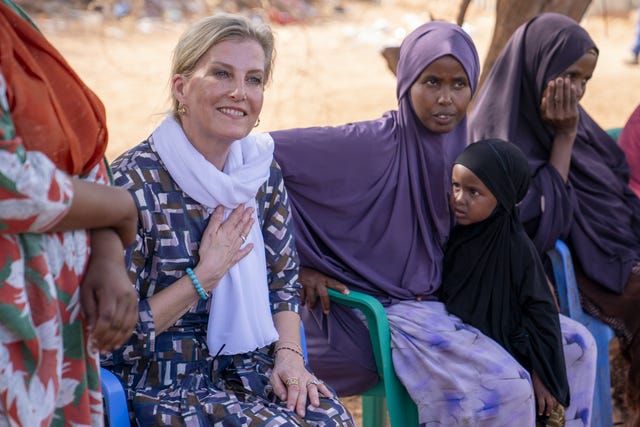 Sophie puts her hand on her heart as she sits with the wives of Somali soldiers in a Somali village