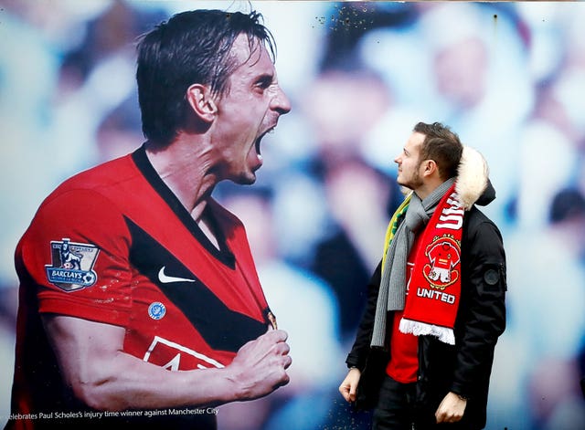 A Manchester United fan admires a photograph of former player Gary Neville outside Old Trafford. Neville is pictured celebrating a derby win at Manchester City in 2010. It proved to be another victorious day for United as they thrashed Norwich 4-0 thanks to a Marcus Rashford brace and goals from Anthony Martial and Mason Greenwood