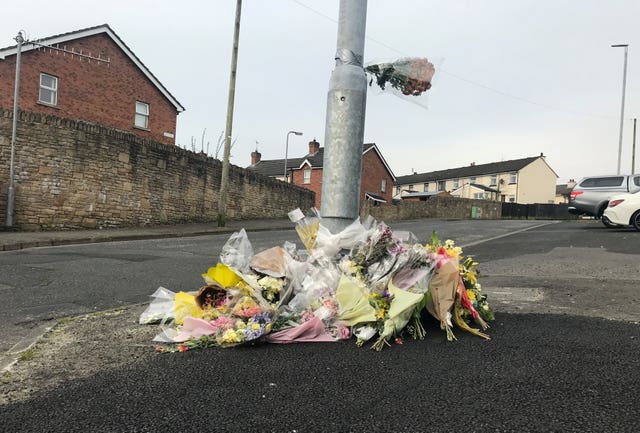 Floral tributes surrounding the base of a lamppost on a street