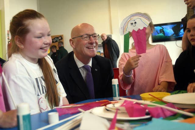 Scottish First Minister and SNP leader John Swinney joins in with children during an arts and crafts session during a visit to the Jeely Piece Club in Glasgow