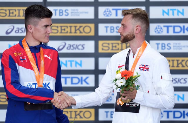 Rivals Jakob Ingebrigtsen and Josh Kerr, wearing medals, shake hands 