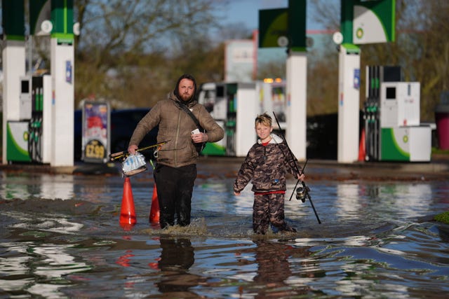 A man and a child walking through flood water with fishing rods