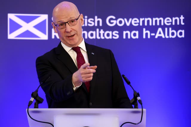 John Swinney pointing while speaking from a lectern