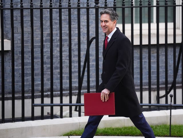 Ed Miliband smiling while walking on Downing Street carrying his red ministerial folder