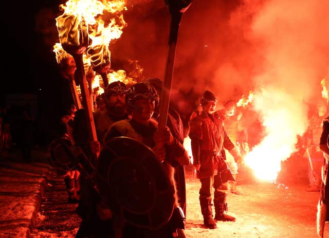 A flare is fired to light the torches of the Jarl Squad as they march through Lerwick ahead of the Galley being set on fire on Shetland Isles during the Up Helly Aa Viking festival