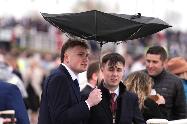 A racegoer holds an umbrella which is inside out on Grand National Day of the Randox Grand National Festival 2026 at Aintree Racecourse