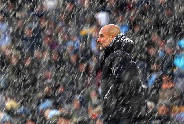 Manchester City manager Pep Guardiola stands in snow during a Premier League match at the Etihad Stadium