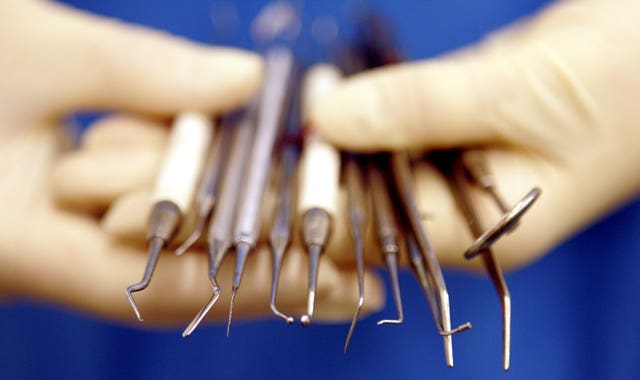 A dental nurse holds dental instruments