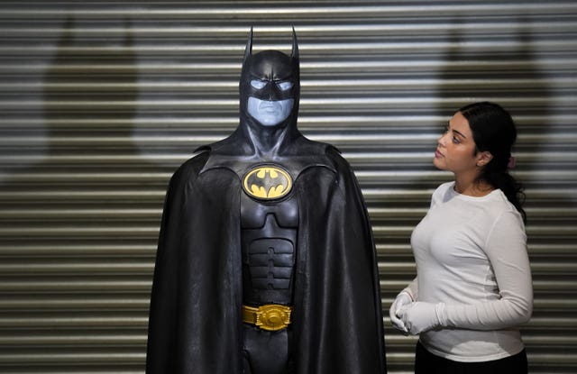 A Propstore employee looks up at Michael Keaton’s batsuit