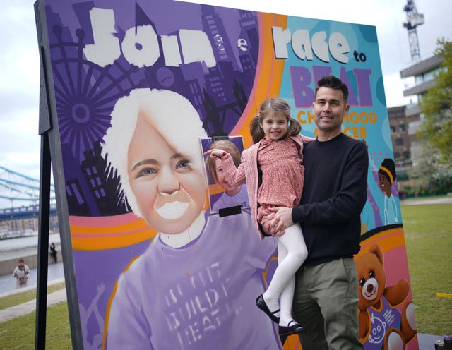 Six-year-old Sienna Halls with her father Gareth, from Ruislip in London, next to a mural at Potters Fields Park in London 