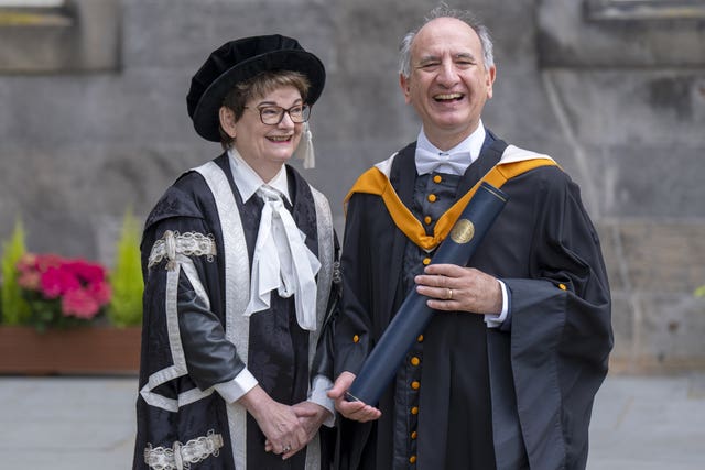 Writer Armando Iannucci and University of St Andrews principal Professor Dame Sally Mapstone smile while posing for photographers after the graduation ceremony