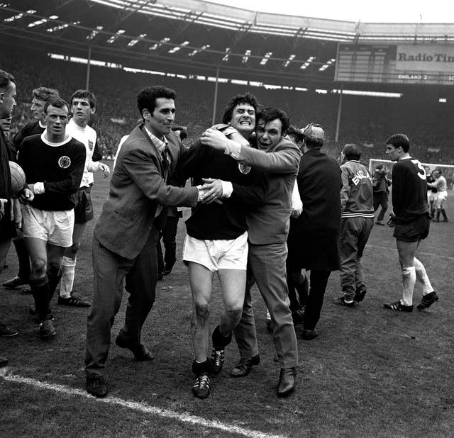 Scotland’s Jim Baxter (centre) is enthusiastically hugged by overjoyed fans who invaded the Wembley Stadium pitch after England had been beaten 3-2 in 1967 