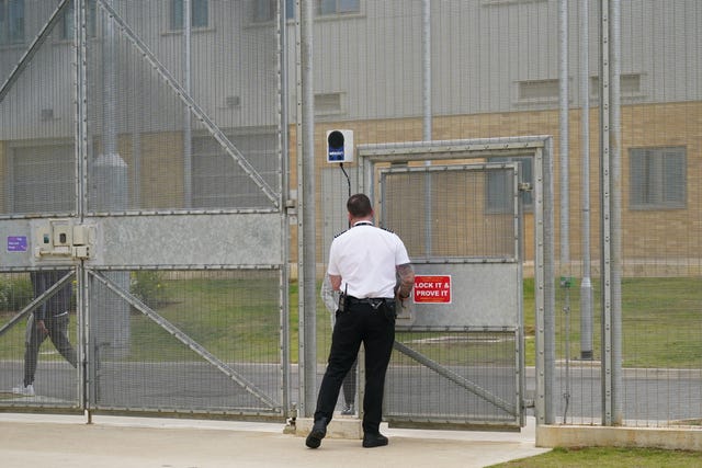 A person in uniform at a door in a fence at a prison