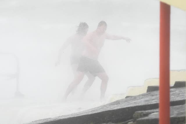 Swimmers run from the spray on Blackrock diving tower in Salthill, Galway during Storm Amy 