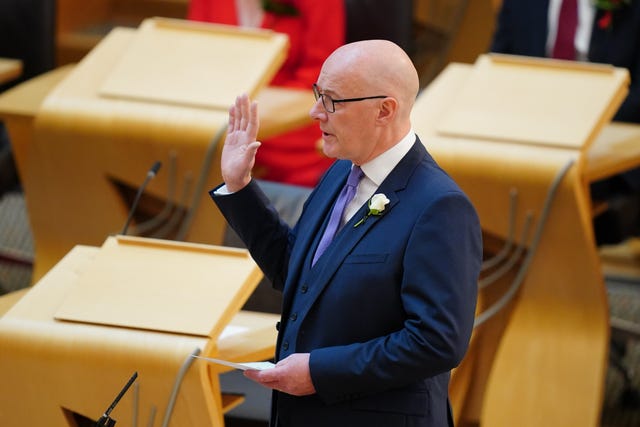John Swinney with his right hand raised, taking his oath in Holyrood