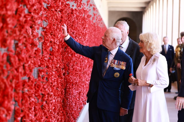 The King reaches out to touch the wall of poppies at the Australian War Memorial in Canberra