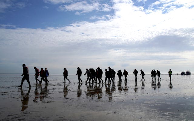 A group of people thought to be migrants walk up the beach after being brought in to Dungeness, Kent (Gareth Fuller/PA)