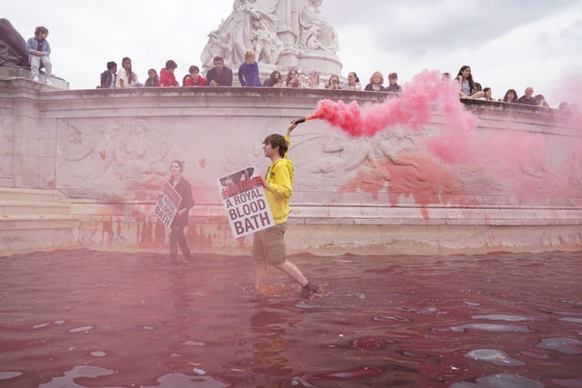 Protesters let off flares as they stand in the fountain at the Queen Victoria Memorial