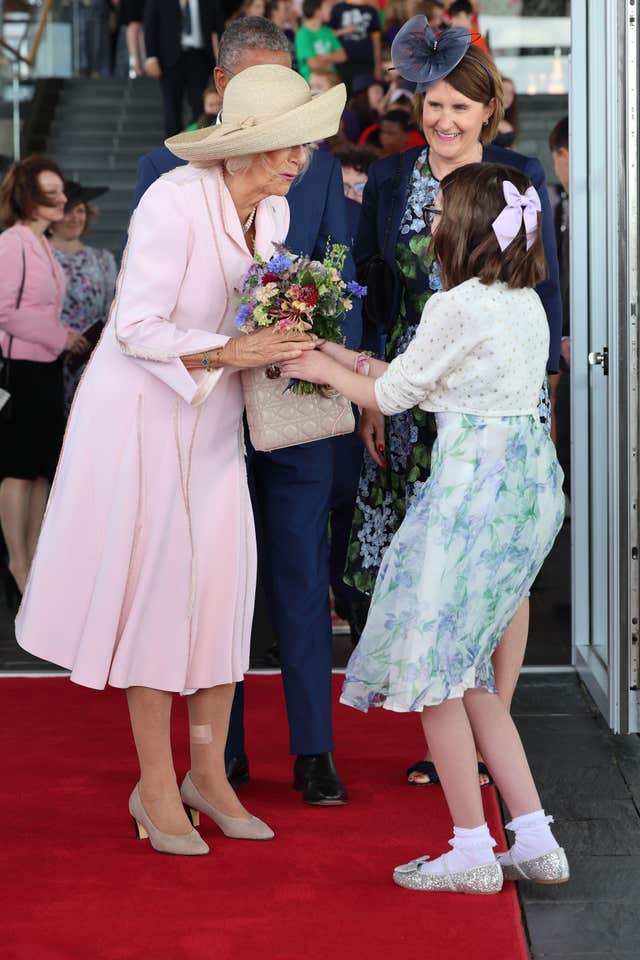 Camilla receives a bouquet of flowers from a young girl
