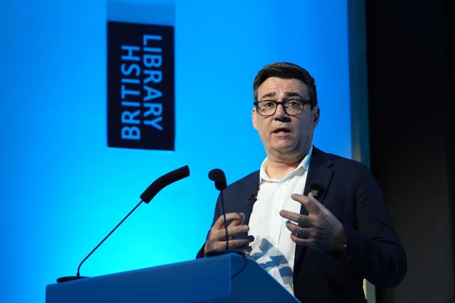 Andy Burnham speaking into a microphone behind a lectern