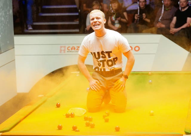 A Just Stop Oil protester jumps on the table and throws orange powder during a match between Robert Milkins and Joe Perry