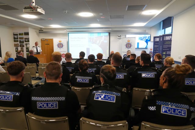 Seated police officers listen to a briefing