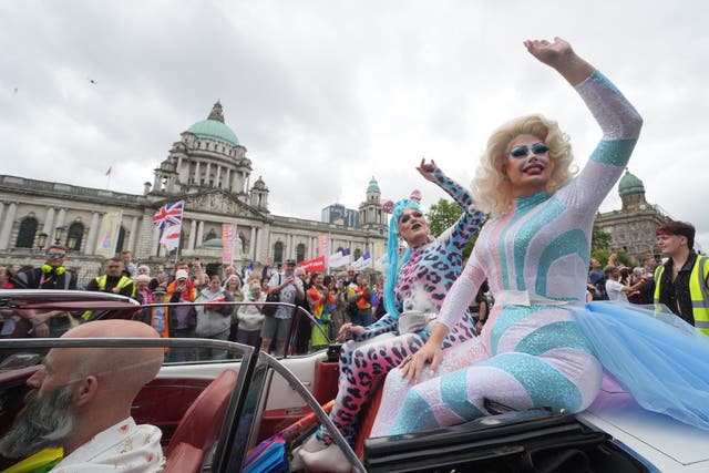 Two drag queens waving from a car