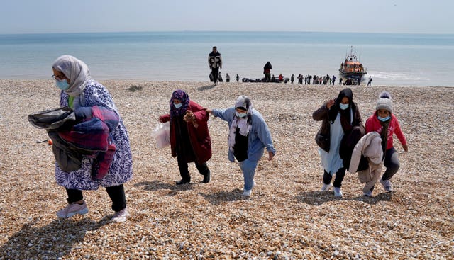 People thought to be migrants making their way up the beach after arriving on a small boat at Dungeness in Kent