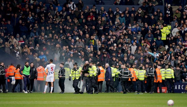West Brom's Kyle Bartley, foreground left, looks on as police officers deal with crowd trouble in the game against Wolves