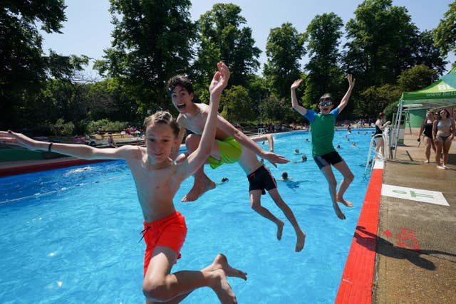 A group of friends jump into the pool as people enjoy the hot weather at Jesus Green Lido in Cambridge