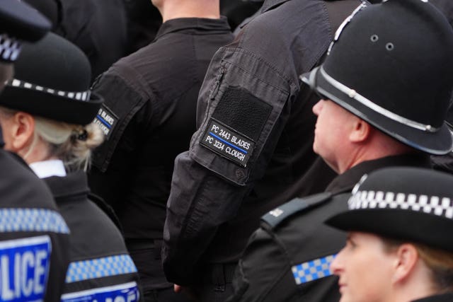 A police officer wears a black armband embroidered with the names of two colleagues who were killed