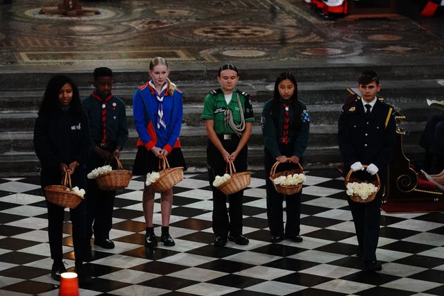 Young people wait to hand out white roses during a service of thanksgiving at Westminster Abbey in London on the 80th anniversary of VE Day