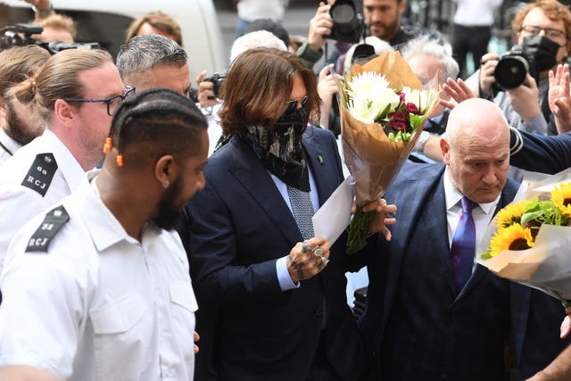 Actor Johnny Depp receives flowers as he arrives at the High Court in London 