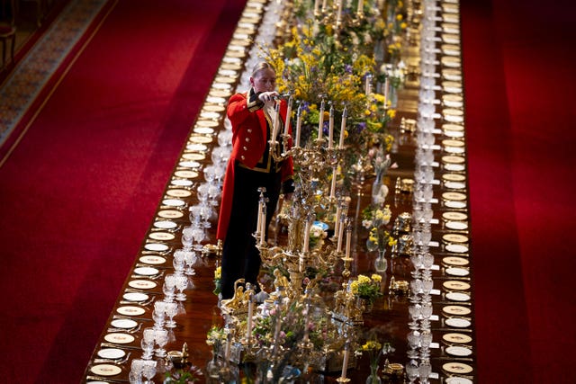A member of Royal Household staff lights a candle during table preparations