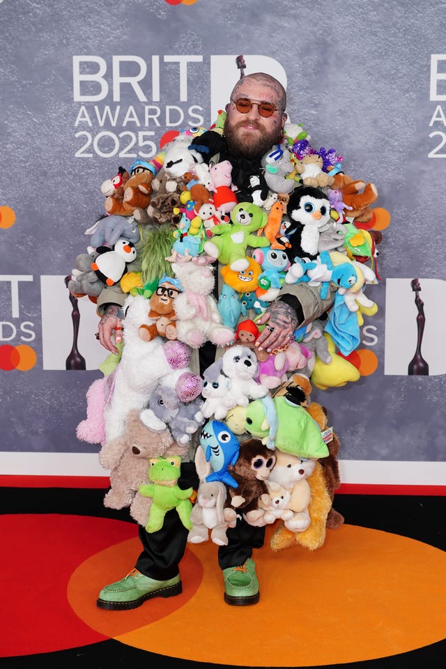 Teddy Swims wearing a coat donning stuffed animal toys on the Brit Awards red carpet