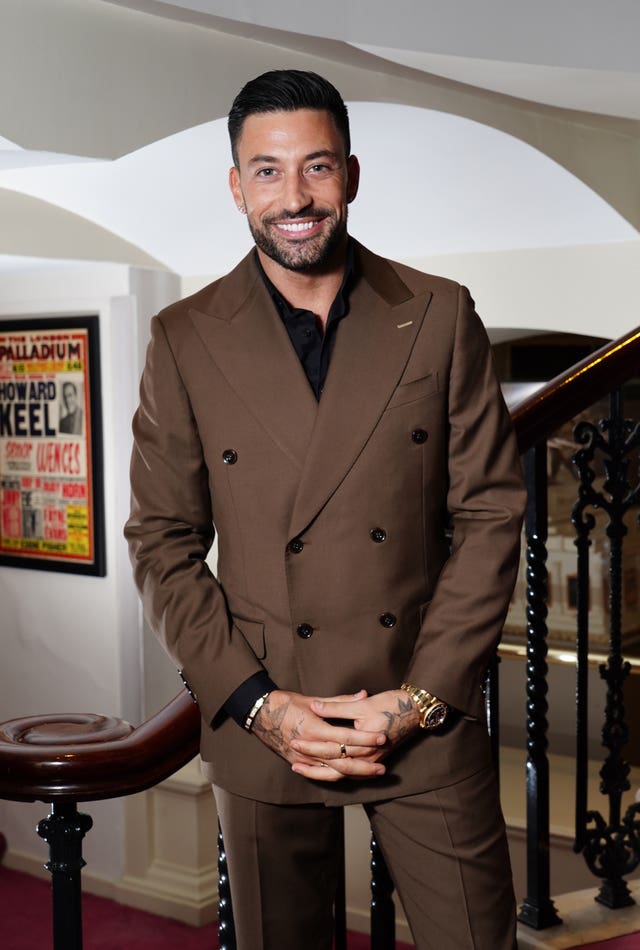 Giovanni Pernice wearing a brown suit standing near a staircase