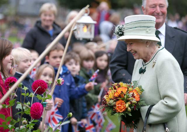 Queen with flowers speaks to children